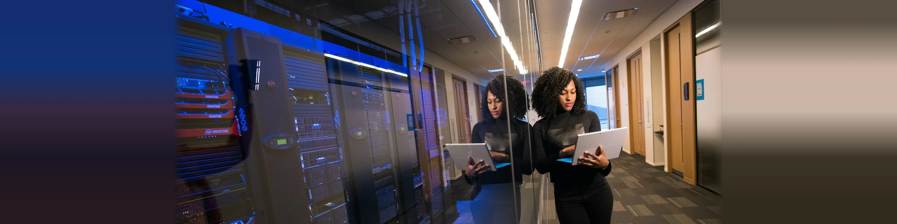 Engineer with a laptop checking servers in a data center aisle