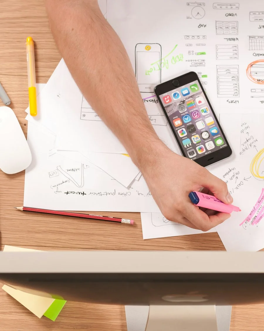 Product team sketching app ideas on paper beside a smartphone